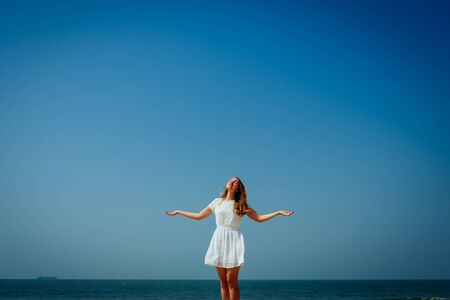 Beautiful Girl with Long Hairs in White Dress Enjoy and Relax on The Beach. Travel and Vacation.