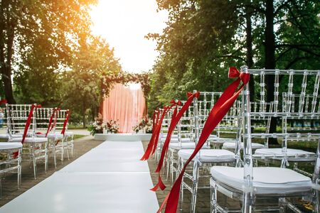 Arch decorated with fresh flowers and fabric for wedding ceremony outdoor. Solemn wedding registration in the park.の写真素材