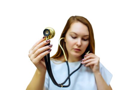 Beautiful young doctor woman using stethoscope isolated on white background. A female doctor with a stethoscope listening to empty space. Healthcare personnel in white robe, medical concept.の写真素材