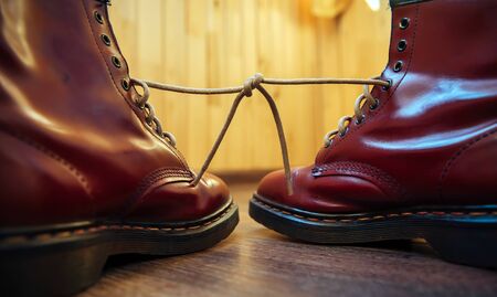 Stylish bright red boots with thick white laces tied together, close-up. April Fools' day, pranks and fun.の写真素材