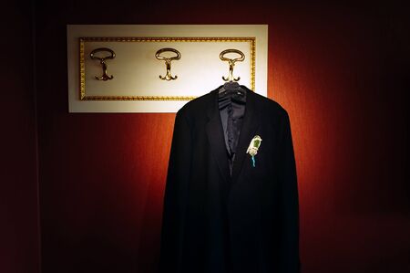 Vintage photo: black wedding suit hanging on a hanger. Boutonniere of flowers on the jacket of the groom.の写真素材