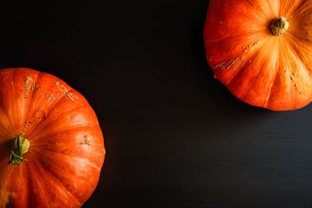 Pumpkins on black wooden table, top view. Halloween background with copy space. Autumn still life with orange pumpkins dark background. Fall season, thanksgiving holiday.の写真素材