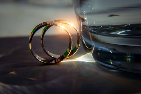 Gold rings of the newlyweds shine and reflect the light, close-up, blurred background. Abstract photo, wedding accessories.の写真素材