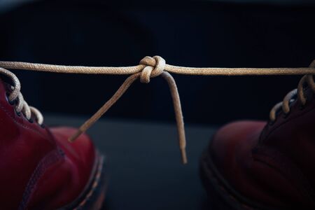 Stylish bright red shoes with thick white laces tied together, close-up, selective focus, space for text. April Fools' day, pranks and fun.の写真素材