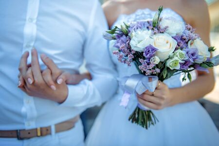 New marriage couple. Bride with wedding bouquet holds the groom's arm. Stylish newlyweds. Wedding concept.の写真素材