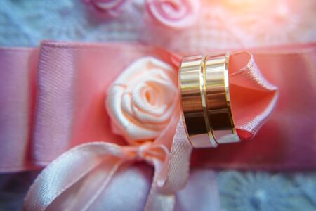 Classic gold wedding rings on pink ribbons, close-up, selective focus. Vintage photography of the wedding day.の写真素材