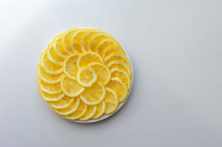 Lemon cut into slices on a white plate. Juicy round pieces of yellow lemon. Citrus is a source of vitamin and ascorbic acid.の写真素材