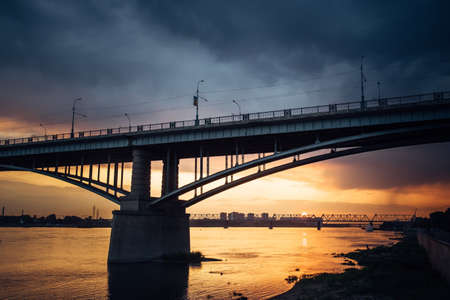 Urban evening landscape. Road bridge over the Ob river at sunset. Fantastic clouds in the dark sky.の写真素材
