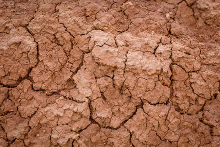 Close up image of brown dry soil texture. Abstract pattern of red-hot cracked clay. Lifeless desert...