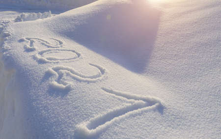 Coming 2021 year outlined on the snow winter background. Inscription 2021 on the snowdrift in...