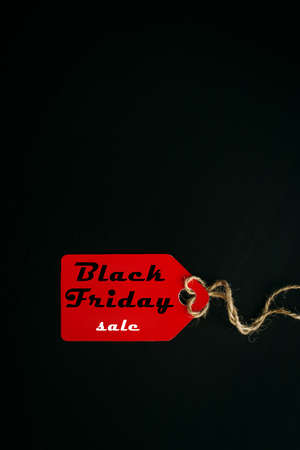 Black friday shopping sale concept. Text on red tag on black wooden background. Vertical image, copy...