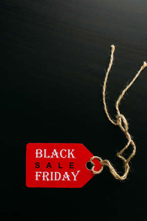 Black friday shopping sale concept. Text on red tag on black wooden background. Vertical image, copy space.の写真素材
