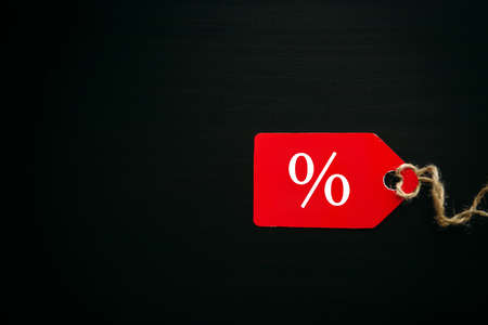 Black friday shopping sale concept. Text on red tag on black wooden background in sunlight. Copy space.の写真素材