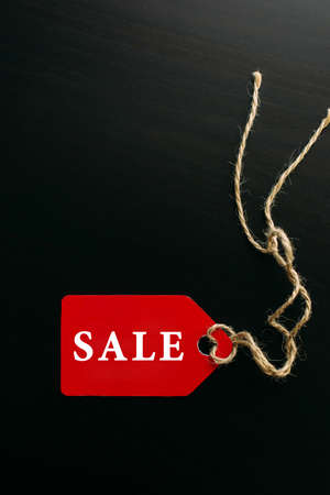 Black friday shopping sale concept. Text on red tag on black wooden background. Vertical image, copy space.の写真素材