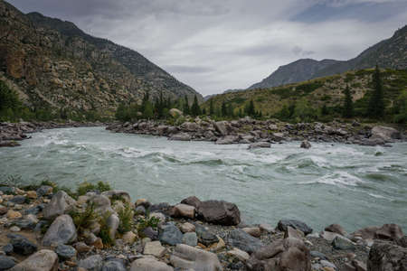 Rapid flow of water in mountain river on the background of rocks and overcast sky. Area for rafting, high level of difficulty.の写真素材