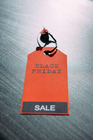 Red tag with inscription on dark wooden background in stylish design, close-up. Concept of black Friday. Final sale in America. Season of total discounts. Image for advertising with copy space.の写真素材