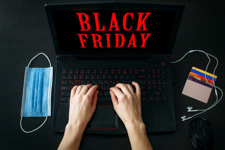 Black Friday, lettering promotional sale on laptop screen. Woman making purchases online. Safe shopping, ordering goods via the Internet.の写真素材