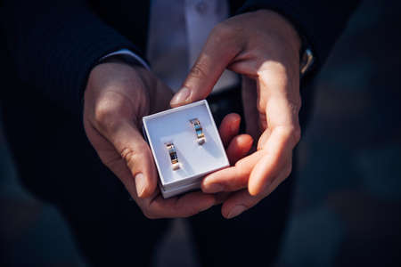 Groom holding small box with gold wedding rings.の写真素材
