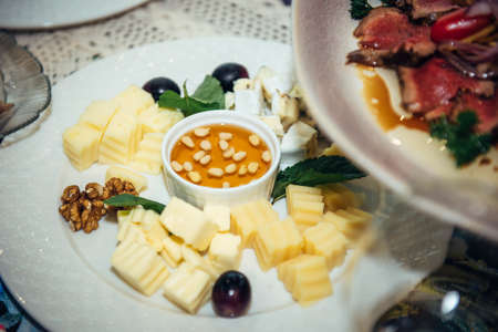 Cheese plate on banquet table, close-up. Dish is served with honey and nuts. Fine food, delicacies.の写真素材