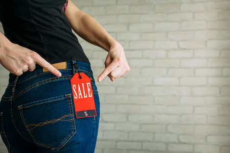 Woman tries on clothes and points to the Black Friday tag.の写真素材