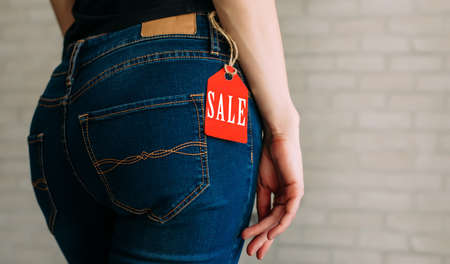 A woman's buttocks wearing blue casual denim pants on gray brickの写真素材