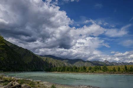 Majestic Katun river surrounded by rocky mountains, wooded banks against a blue sky with white clouds. Beautiful natural landscape.の写真素材
