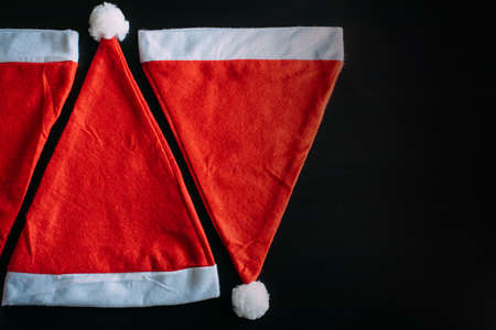 Red Father Christmas hats isolated on black background, top view, close up. Santa's hat with space for text. New year concept.の写真素材
