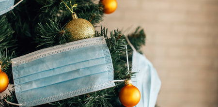 Christmas tree decorated with blue medical masks and golden balls, close up. Concept of 2021 new year amid the coronavirus pandemic. Symbol of holiday in quarantine. Image with space for text.の写真素材