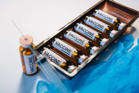 Medical syringe and vaccine in vial, box with ampules, select focus. Inscription on the label, close up. World coronavirus covid-19 vaccination concept.の写真素材