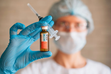 Blurred image: doctor holding syringe and coronavirus Covid-19 vaccine vial. Vaccination, pharmaceutical research concept.の写真素材