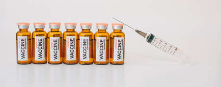 Line of coronavirus covid-19 vaccine vials and medical syringe with needle up on white background. Banner for advertising of pharmaceutical products with copy space.の写真素材