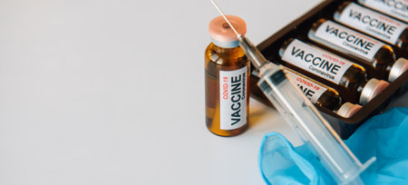 Medical syringe and vaccine in vial, box with ampules on white background with copy space. Inscription on the label, close up. Coronavirus covid-19 mass vaccination concept.の写真素材