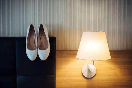 Classic white shoes for young bride, minimalistic image. Wedding women's shoes in home interior. Preparation for the wedding celebration.の写真素材