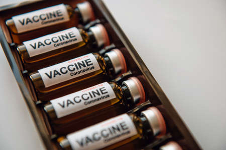 Bottles of vaccine to fight the coronavirus pandemic. Sars-cov-2 / COVID-19. Some ampoules with vaccine in a box on white background, close up.の写真素材