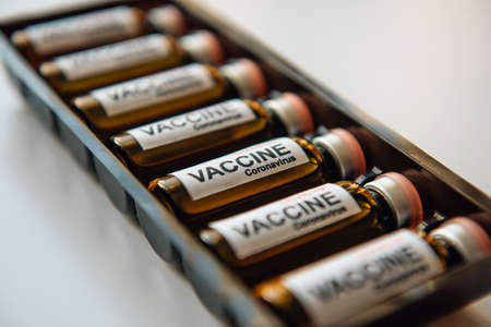 Bottles of vaccine to fight the coronavirus pandemic. Sars-cov-2 / COVID-19. Some ampoules with vaccine in a box on white background, close up.の写真素材