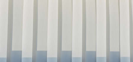 Abstract geometric vertical lines white and gray gradient color. Repeating pattern, background texture, design of striped lines. Blinds illuminated by the sun, close-up.の写真素材