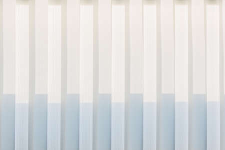 Abstract geometric vertical lines white and gray gradient color. Repeating pattern, background texture, design of striped lines. Blinds illuminated by the sun, close-up.の写真素材