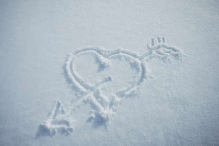 Heart with arrow, drawn in snow. Love symbol painted on white snowy background. Romantic...