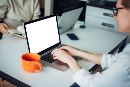 Close-up of caucasian woman's hands typing on laptop keyboard. Empty screen, space for text. Blurred...