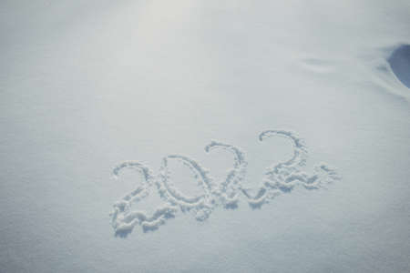 Drawing on white snow in sunlight. New Year's date, figures 2022, close-up.の写真素材