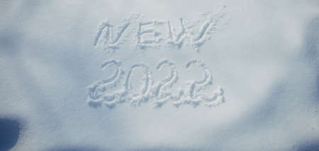 Drawing on white snow in sunlight. New Year's date, figures 2022, close-up. Winter holiday concept.の写真素材