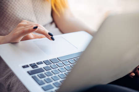 Close up young woman's hands with bright manicure on laptop touchpad, selective focus.