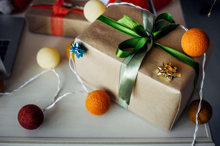 Christmas still life, close-up. Gift box made of craft paper decorated with ribbons, electrical garland in the form of colorful balls.の写真素材
