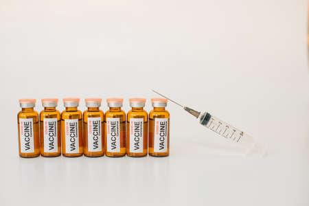 vaccine vials and medical syringe with needle up on white background. Vaccination concept. Advertising of pharmaceutical products with copy space.の写真素材
