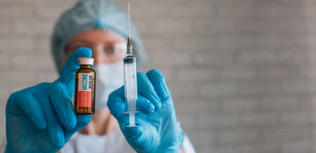 Female doctor or nurse in uniform and blue gloves holds vial and syringe. Focus on label textの写真素材