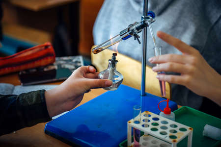 Students conduct experiments in chemistry class. Heating the test tube over the burner, close up.の写真素材