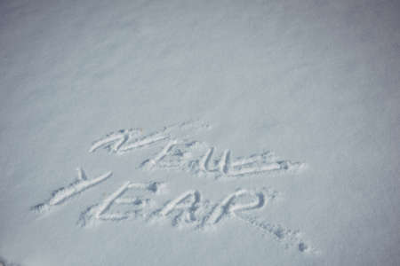 Drawing in the snow, words written by a human hand. New Year's concept.の写真素材