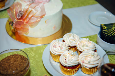 Delicious cupcakes with whipped cream. Exquisite sweets at a festive banquet. Dessert table, close-up.の写真素材