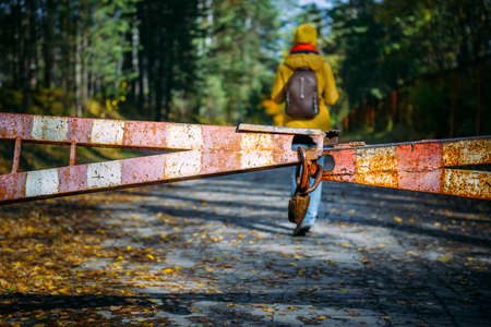 Female silhouette behind a rusty iron gate with a padlock. Woman enters a deserted closed park. Concept of violating prohibitions.の写真素材