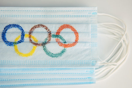 Novosibirsk, Russia - 06.01.2022. Olympic rings painted on medical mask. Stack of surgical masks with Olympic symbols. Concept of olympiad in Beijing 2022.のeditorial素材
